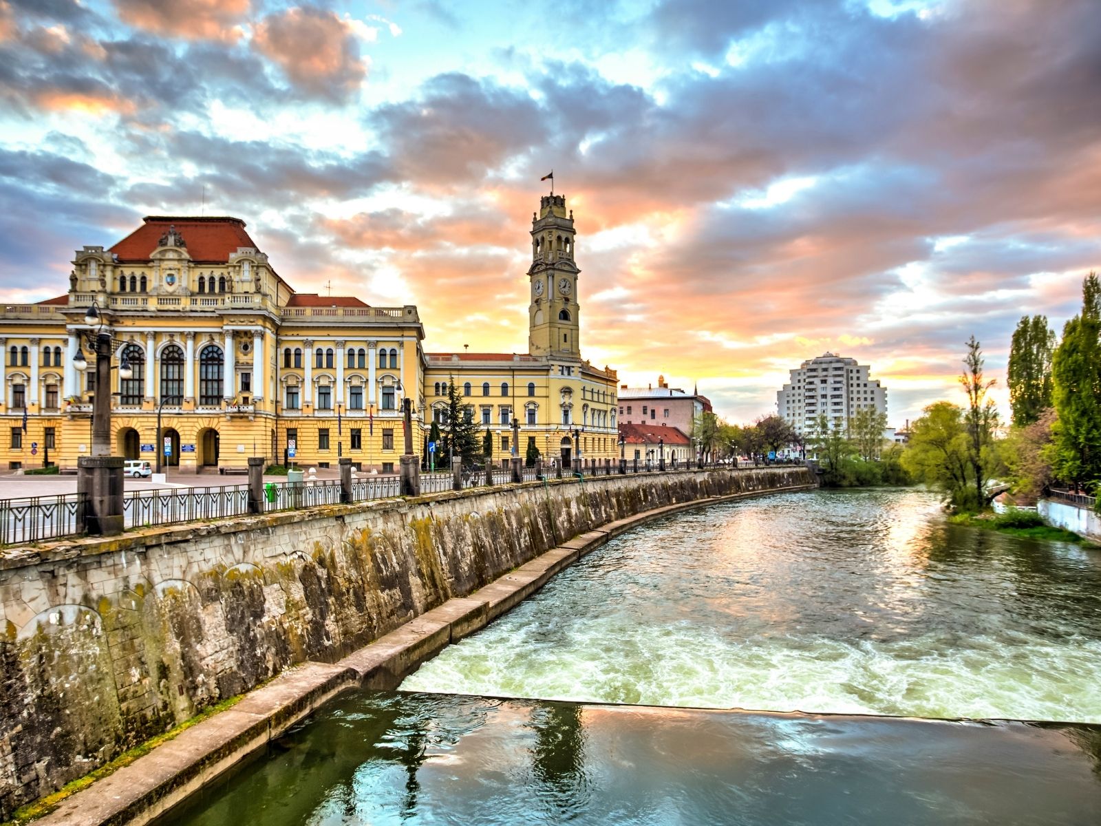 Historic riverside architecture along the Crișul Repede River in Oradea, Romania, at sunset
