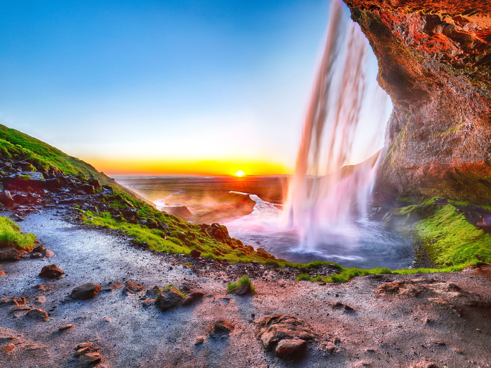Seljalandsfoss waterfall at sunset in southern Iceland with a scenic walking trail behind the cascading falls